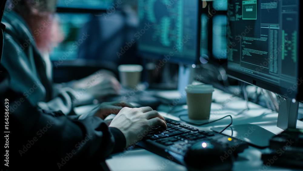 Aufkleber Close-up Shot of Hacker using Keyboard. There is Coffee Cups and Computer Monitors with Various Information.