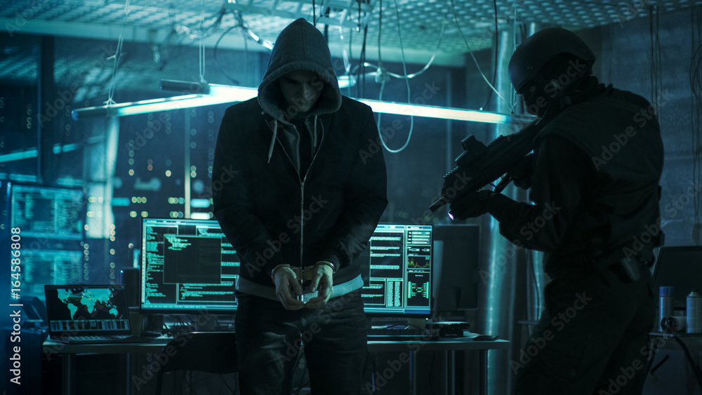 Aufkleber Handcuffed Hacker is Standing and Guarded by Fully Armed Special Forces Soldier. They're in Hacker's Hideout Basement with Multiple Operating Displays.
