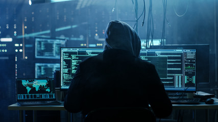 Dangerous Hooded Hacker Breaks into Government Data Servers and Infects Their System with a  Virus. His Hideout Place has Dark Atmosphere, Multiple Displays, Cables Everywhere. - obrazy, fototapety, plakaty