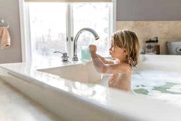 Girl playing with water in bubble bath 