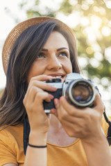 Smiling young woman using a camera to take photo.