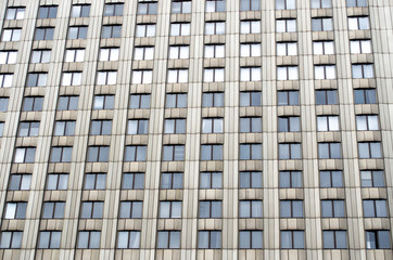 Fototapeta premium Many windows a tall urban building of monophonic color