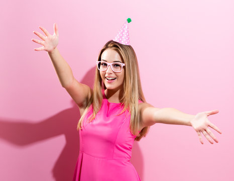 Young woman with party hat on a pink background