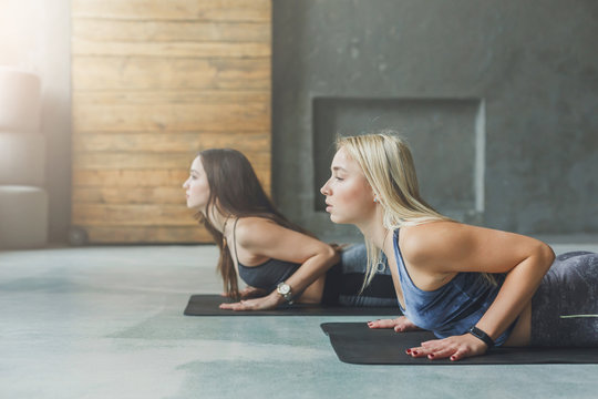 Young women in yoga class, snake pose stretching