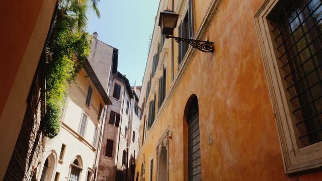 Beautiful narrow street in the old part of Rome, Italy. Medieval buildings covered with ivy. Steadicam shot