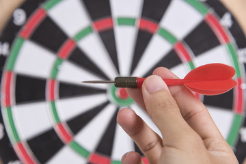 hand holhing red arrow target center of dartboard. concept business goal to marketing success.