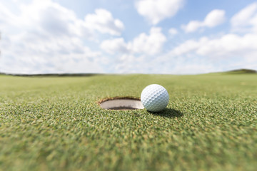 golf ball on lip of cup. Golf ball on green grass in golf course
