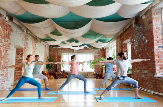group of people doing yoga warrior pose at studio