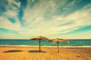Two straw umbrellas on sandy deserted tropical beach