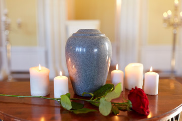 red rose and cremation urn with burning candles - obrazy, fototapety, plakaty