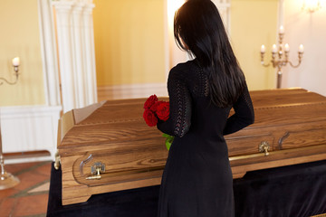 woman with red roses and coffin at funeral