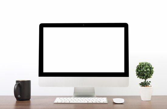 Office monitor computer, mouse on wooden table and white wall background