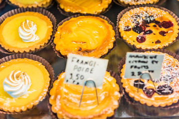 Small lemon meringue tarts with whipped egg whites on display in bakery with signs in French