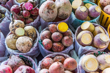 Closeup of different types of turnips root vegetables on display in baskets at farmers market