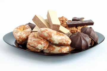 Group of different sweets lying on a black plate.