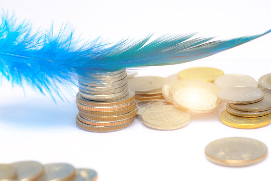 close up and selective focus on blue feather on Thai coins stack with white background. economy , saving money  concept