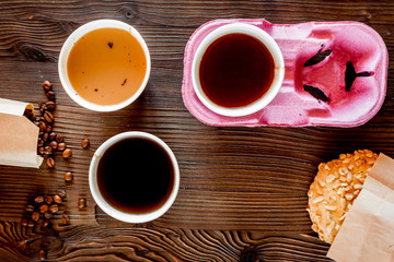 Coffee take out. Coffee cups with covers, coffee beans and cookies on wooden table backound top view copsspace