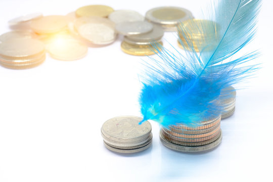 close up and selective focus on blue feather on Thai coins stack with white background. economy , saving money  concept
