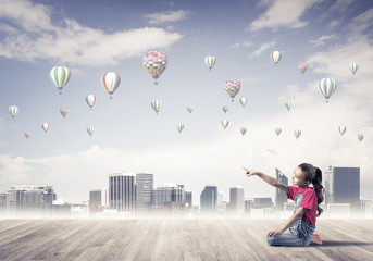 Concept of careless happy childhood with girl pointing at someth