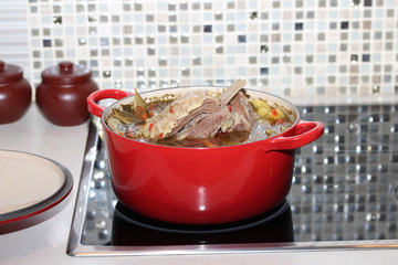 Cooking. Beef stew with potatoes, pepper and carrots in big red round casserole.
