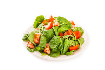 Salad with tomato, cucumber and spinach on the plate isolated on white background