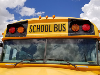 yellow school bus with summer cloud reflection in windshield
