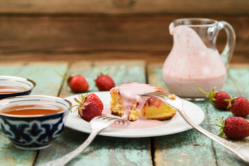 Tasty strawberry cake with cream sauce in glass jar served with fresh berries and black tea