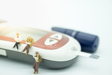 Male, female and businessman miniature figures sitting and reading a book on blood sugar test strip in Glucose meter with lancet use for Medicine, diabetes, glycemia, health care and people concept.