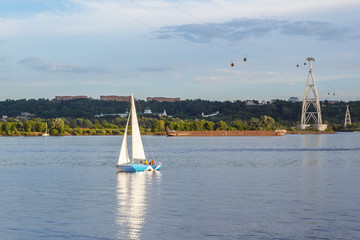 White sailboat on the river on the background of the cable car in Nizhny Novgorod