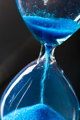 Time is passing. Blue hourglass close up
