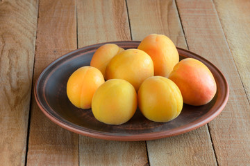 Yellow apricots on a clay plate.