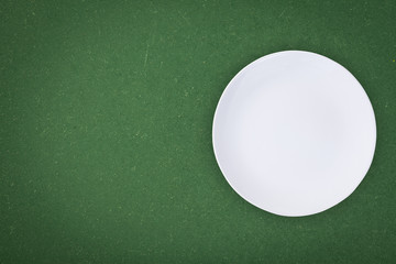 Top view of an empty white plate placed on a blackboard with copy space.