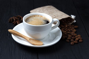 Hot coffee with anise, a wooden spoon and a bag of coffee beans