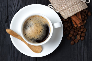 Hot coffee with cinnamon, a wooden spoon and a bag of coffee beans