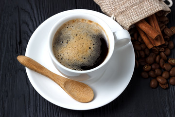 Hot coffee with cinnamon, a wooden spoon and a bag of coffee beans