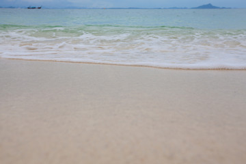 Abstract blurry background of sandy beach with soft waves.