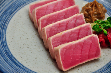 Grilled raw seared tuna on blue tile plate Japanese style