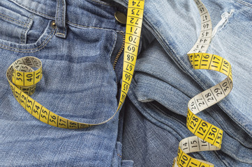 Detail of blue jeans with measuring tape, diet concept.