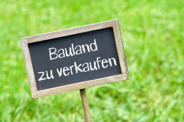 Bauland zu verkaufen - Kreidetafel mit Schrift auf Gras Hintergrund - Bauplatz, Baugrund