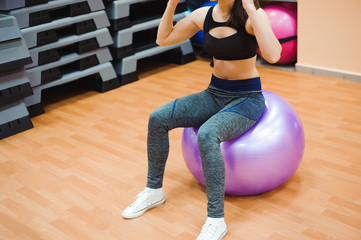 Fototapeta na wymiar Pretty sexual straight fitness woman with musculat body lying on big ball in sport hall training indoor, horizontal picture