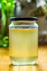 Close up of a jar of honey. Fresh acacia honey, rich in vitamins, minerals, carbohydrates and amino acids. On a wooden table, shallow depth of focus.