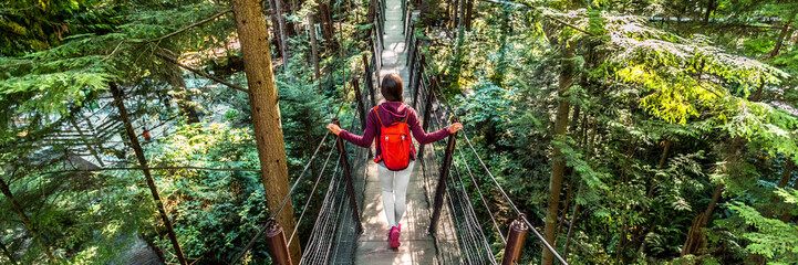 Canada travel people lifestyle banner. Tourist woman walking in famous attraction Capilano Suspension Bridge in North Vancouver, British Columbia, canadian vacation destination for tourism. - obrazy, fototapety, plakaty