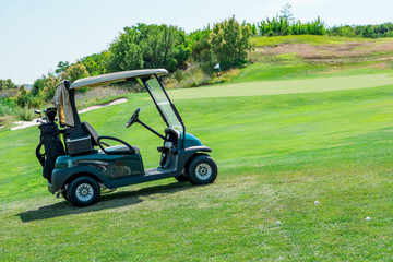 Close up of a golf cart with sticks, a golf course, golf balls and green grass. Concept rest and sport.