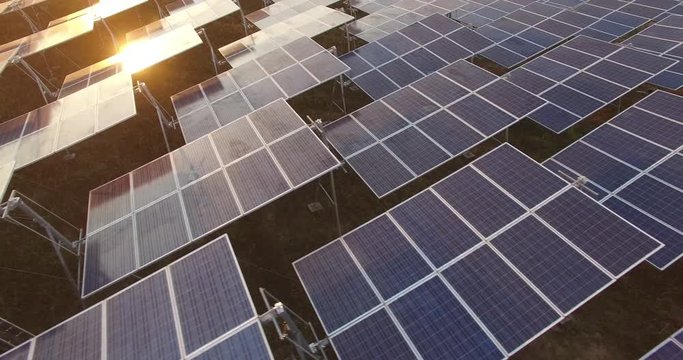 4K Aerial view of Solar Panels Farm (solar cell) with sunlight.Drone flight fly over solar panels field renewable green alternative energy concept in Thailand.