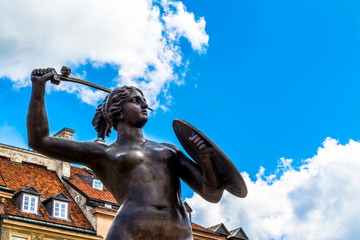 Sculpture of a mermaid in the old town in Warsaw on sunny day with blue cloudy sky. © HappyRichStudio