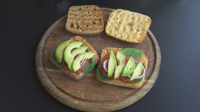 a man making sandwiches with avocado and tomatoes 