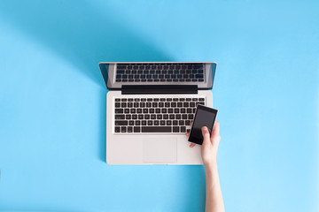 Female hand holding mobile phone on laptop computer, View from above