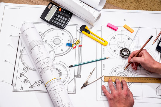 Mechanical engineer with work at technical drawings and work tools
