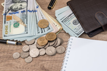 notepad with pen, calculator, dollar bills on desk.