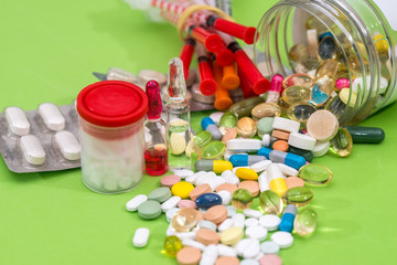 many pills, syringe isolated on green background